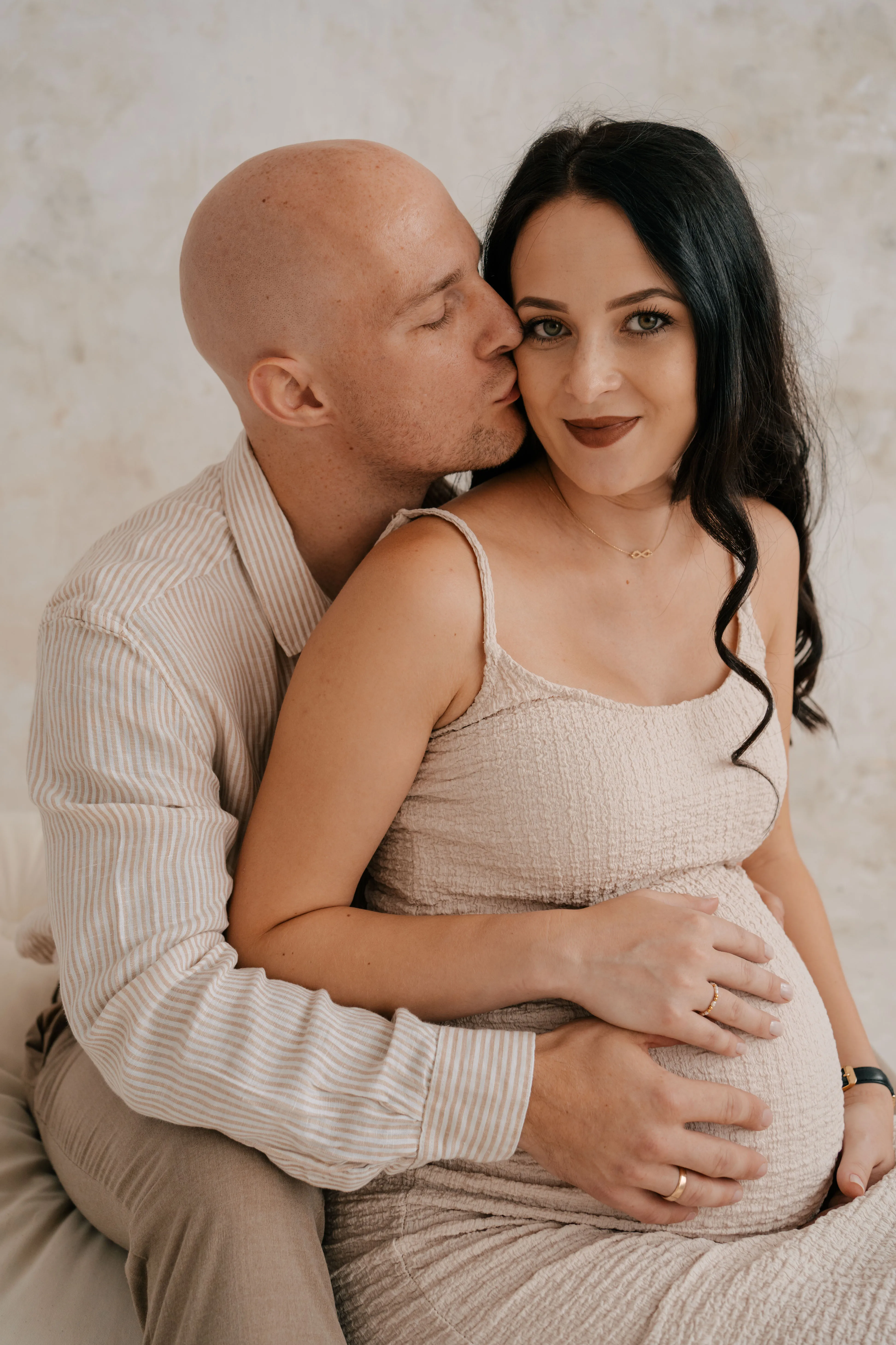 Plenerowa sesja ciążowa w naturze, przyszła mama w zwiewnej sukni na tle zieleni.