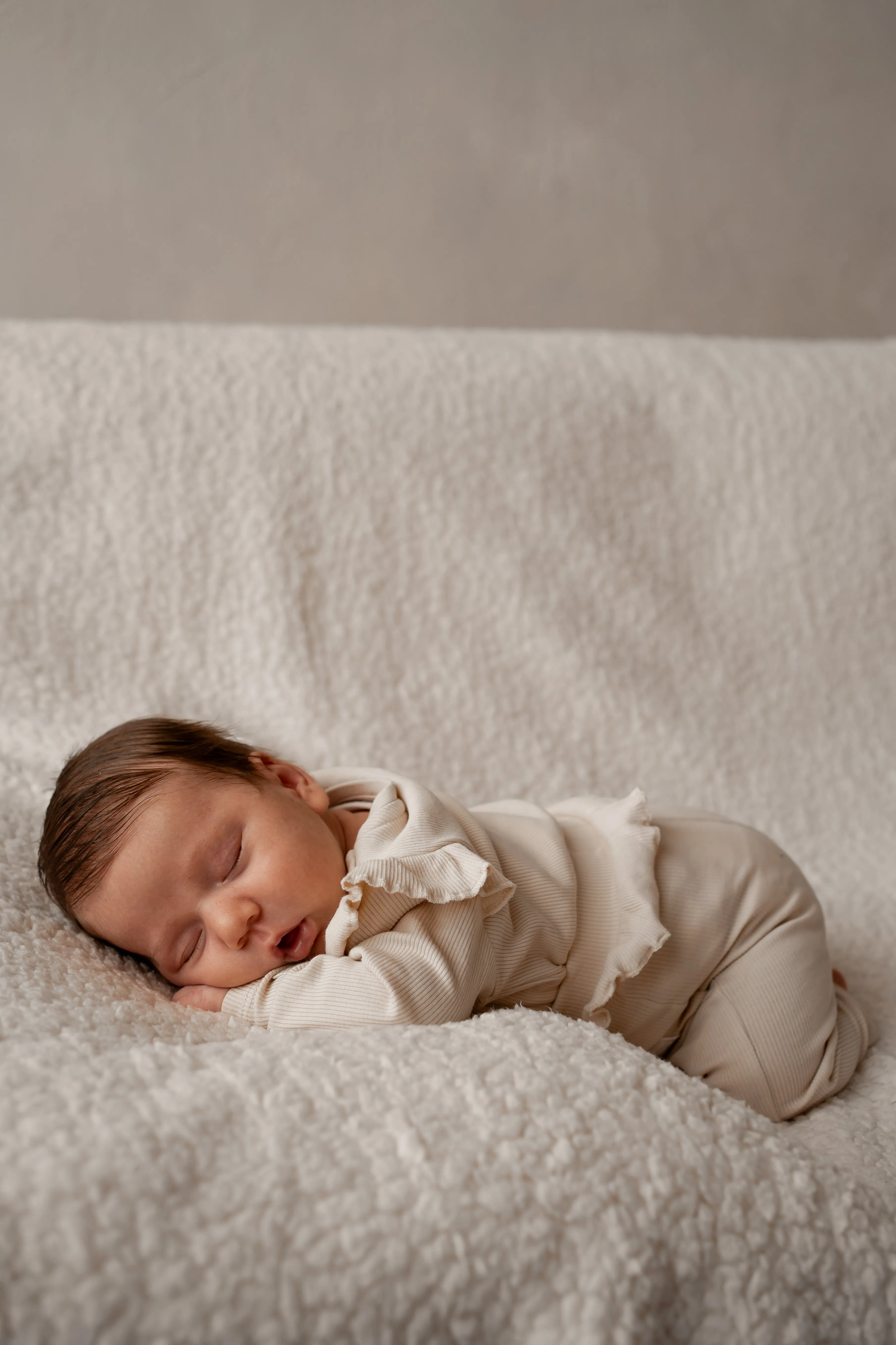 Delikatna sesja noworodkowa lifestyle, maleństwo śpiące w objęciach mamy.