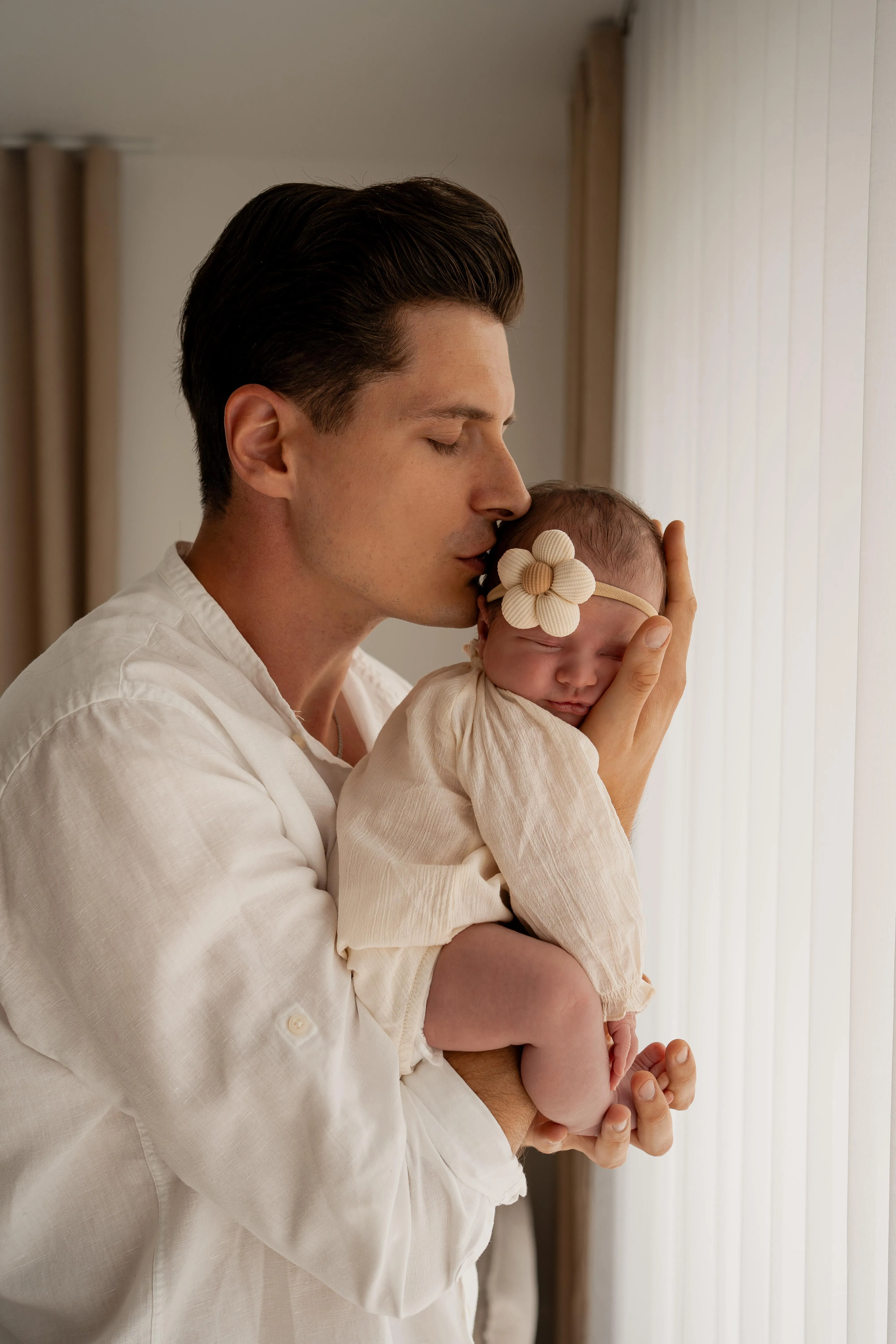 Wzruszająca fotografia noworodkowa, tata trzymający w dłoniach małe stópki swojego dziecka.